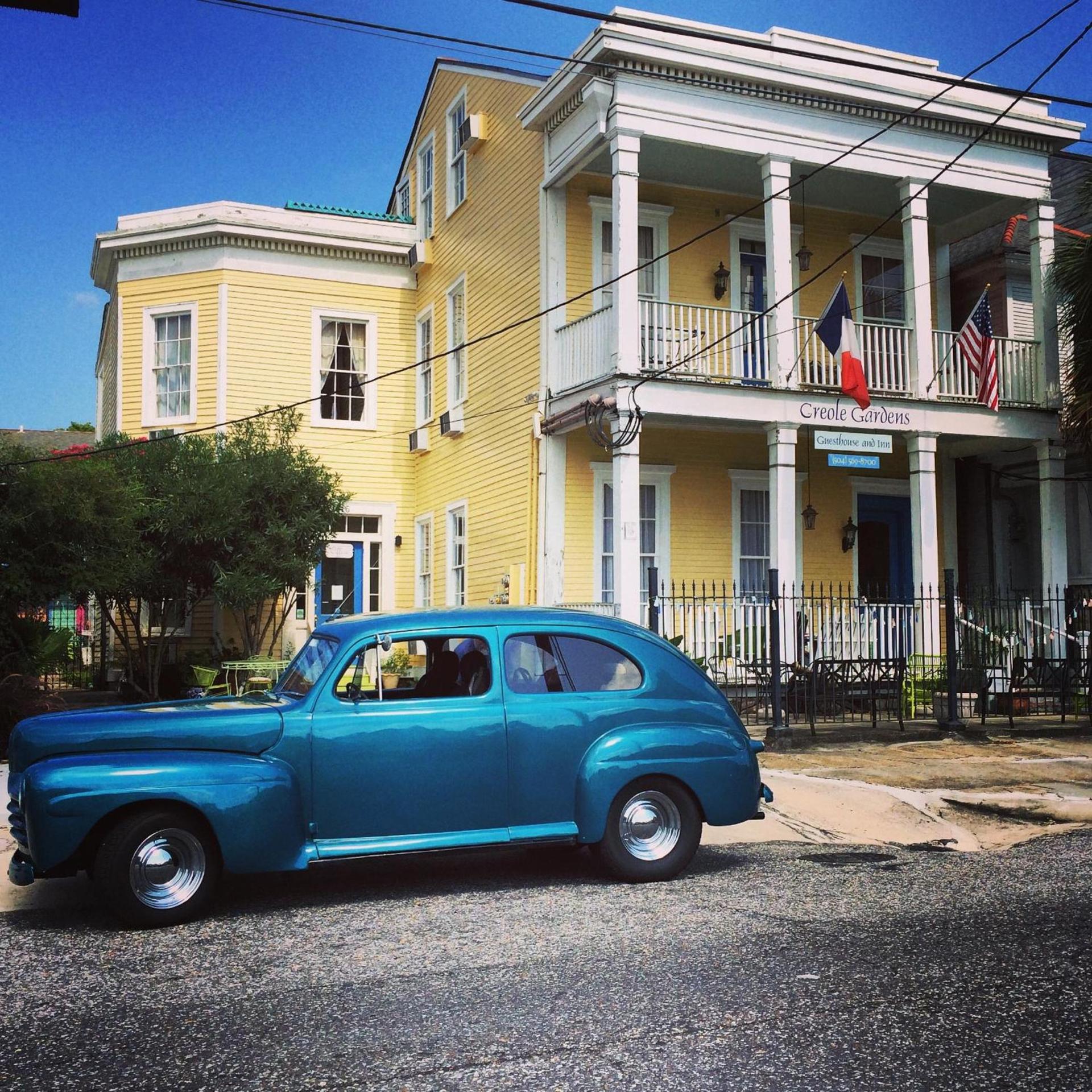 A colorful Creole guesthouse and a vintage car on a sunny New Orleans street