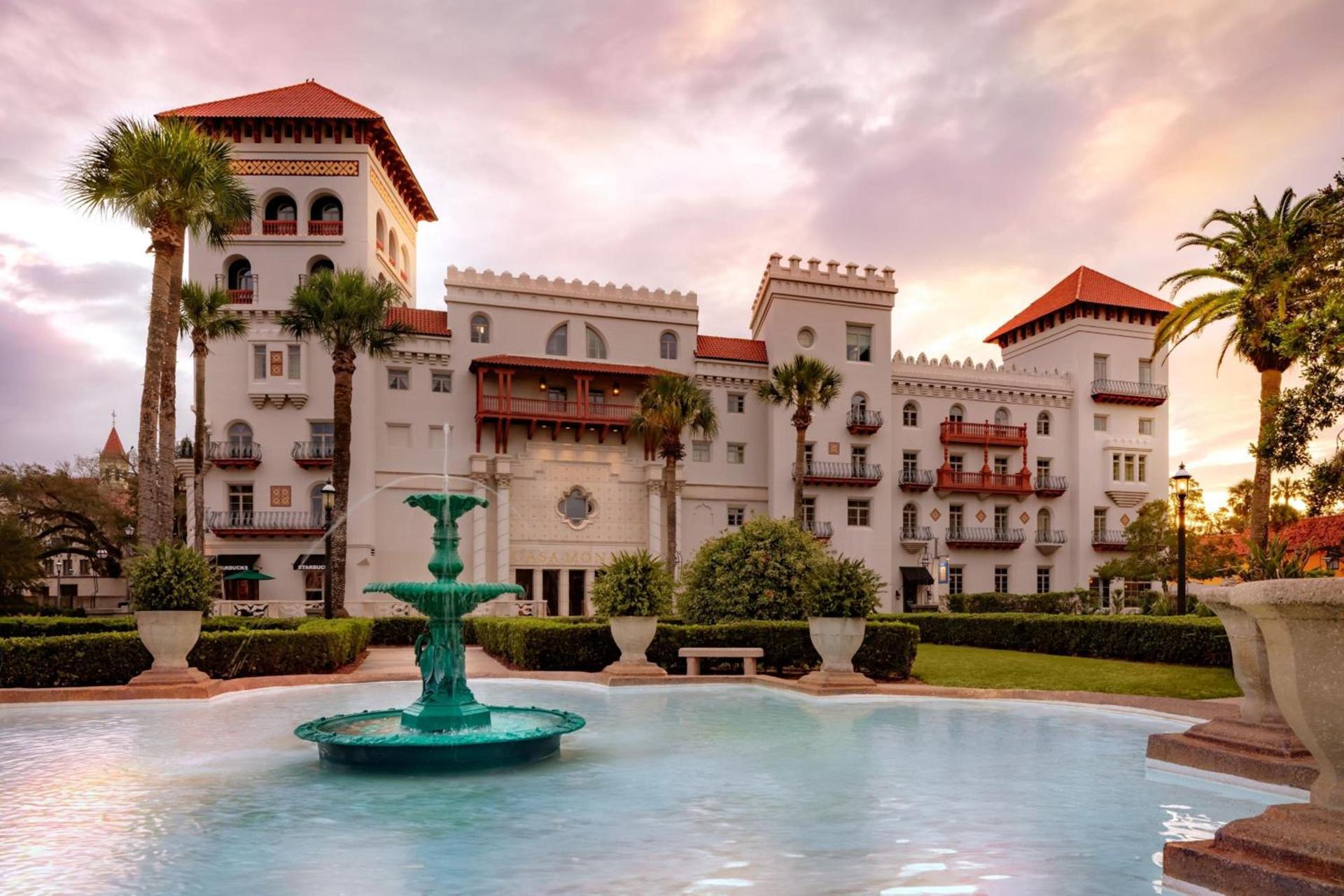 The white Moorish-revival towers and red-tile turrets of a grand 1888 hotel with a fountain and palms at sunset in St. Augustine, Florida