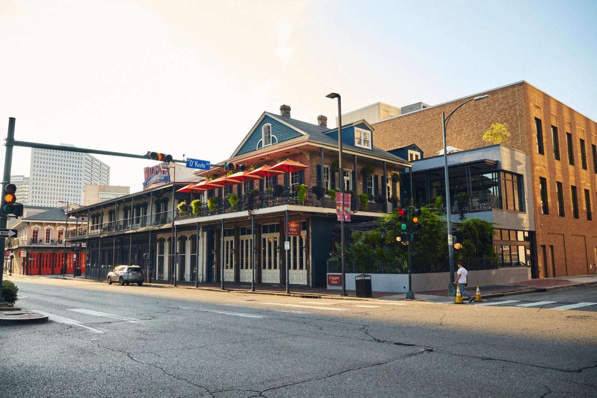 A New Orleans French Quarter corner — wrought-iron galleries, red café umbrellas and warm evening light