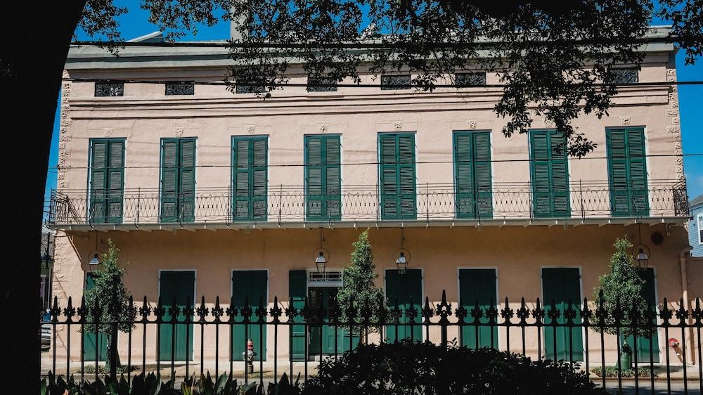 A peach Creole townhouse with green shutters and a wrought-iron balcony on Frenchmen Street in the New Orleans Marigny under a blue sky