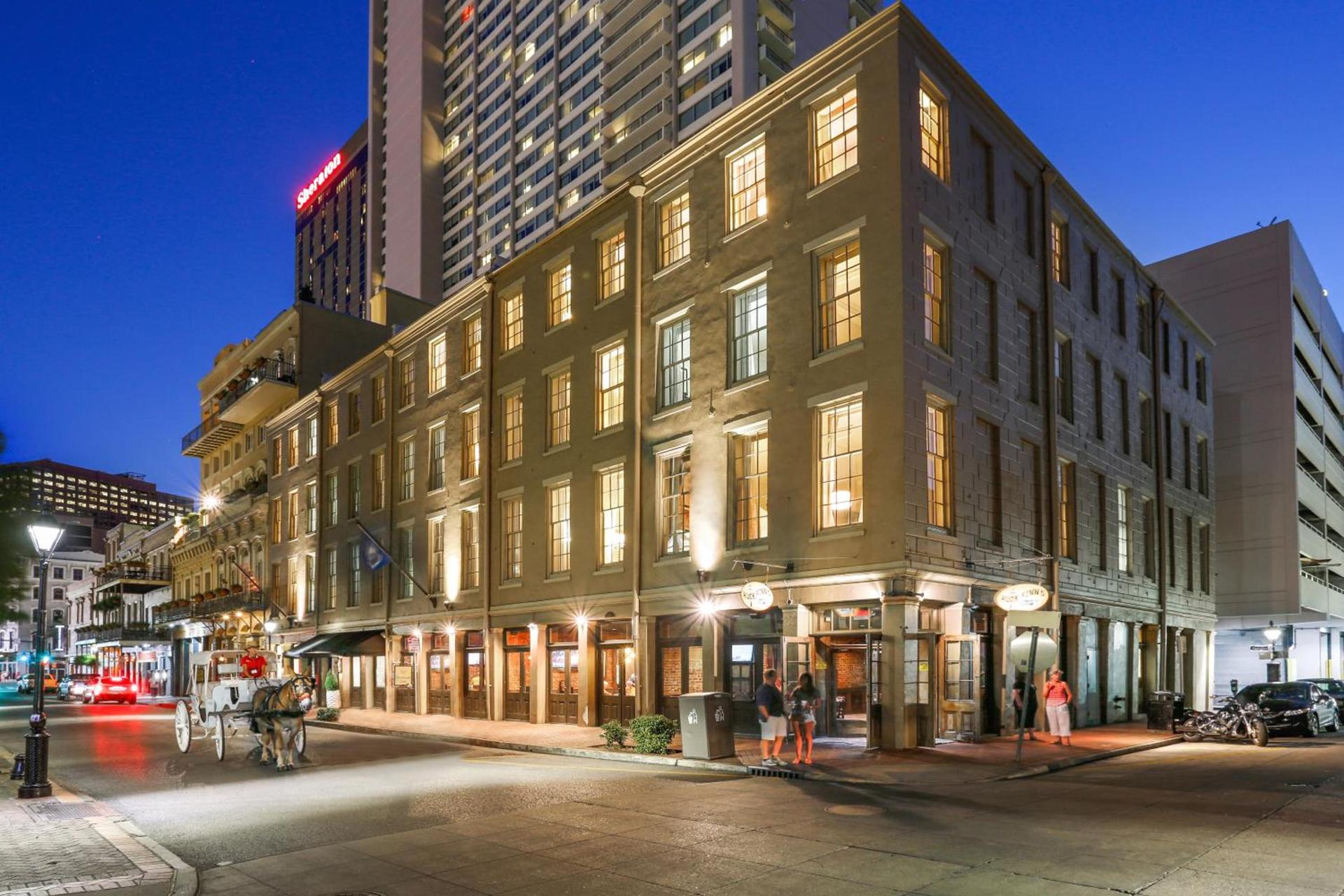 A warm evening on a French Quarter street corner in New Orleans, with lit storefronts and a horse-drawn carriage near the city's best restaurants