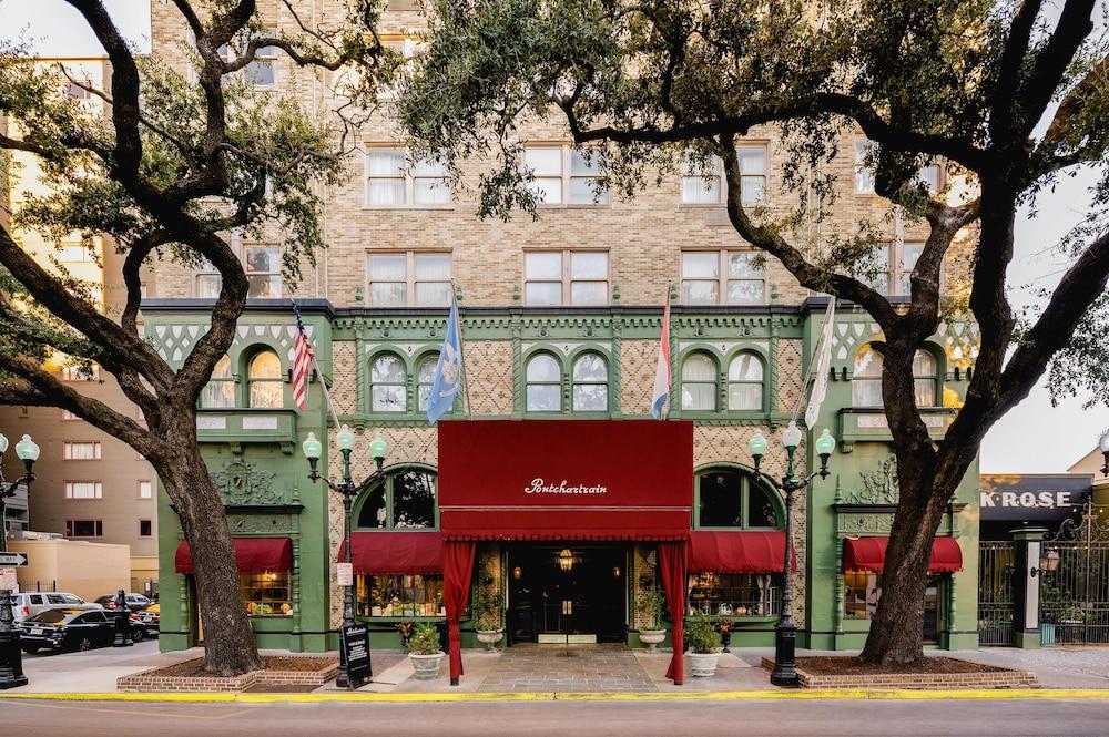 The historic Pontchartrain Hotel in the New Orleans Garden District, a green-tiled facade with red awnings and flags framed by live oak trees